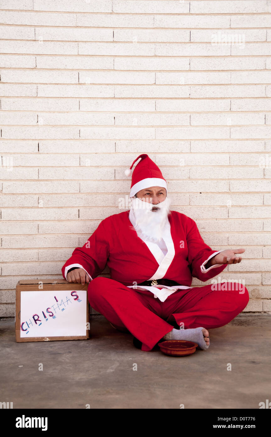 Santa Claus is hit by the crisis and has to beg in the street Stock Photo