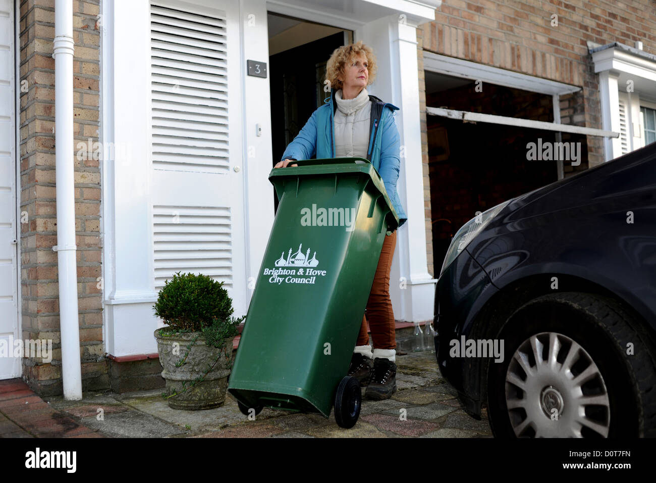 Housewife middle aged woman in putting out the rubbish collection bin ready for the dustmen in Brighton UK Stock Photo