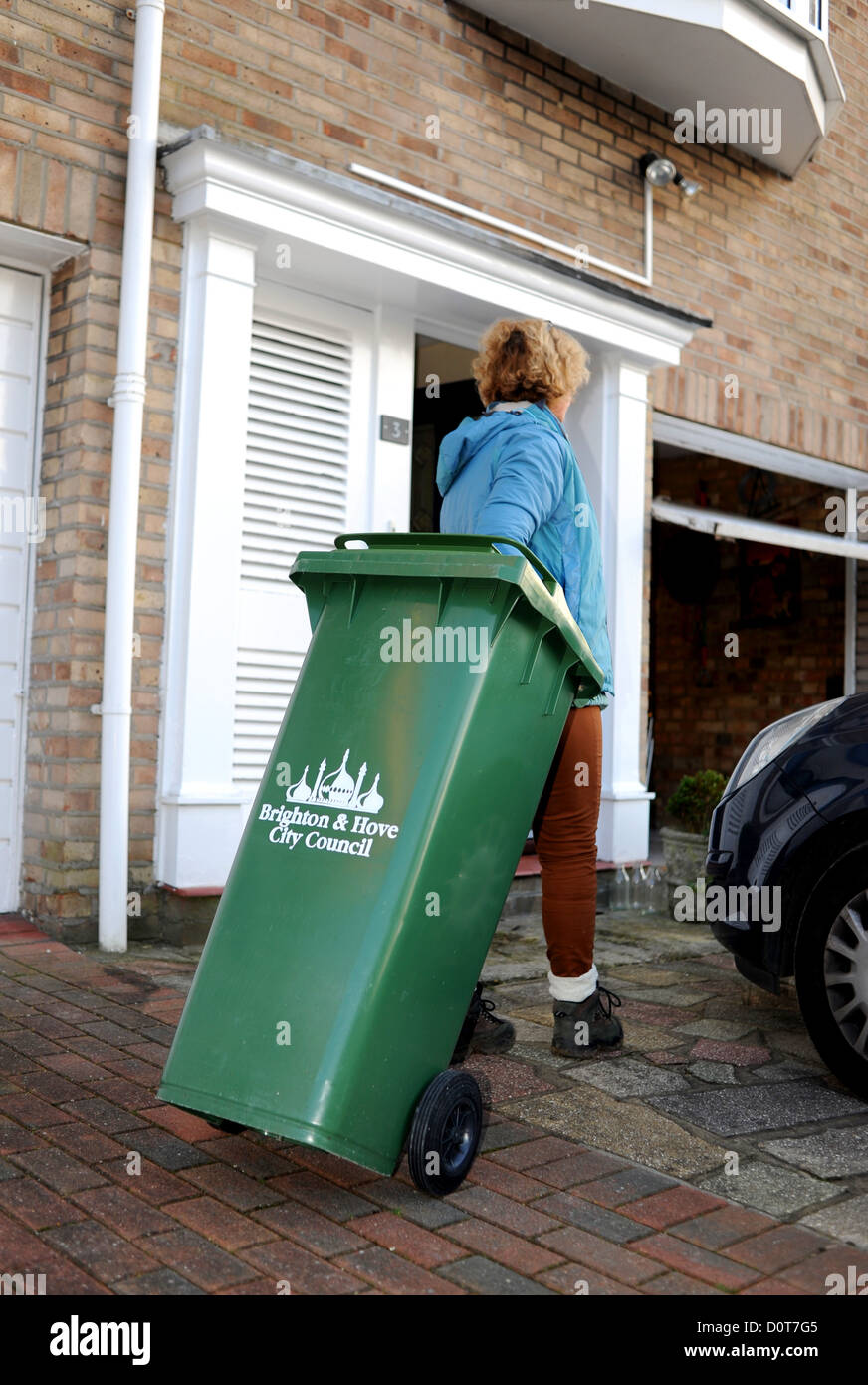 Housewife middle aged woman in putting out the rubbish collection bin ready for the dustmen in Brighton UK Stock Photo