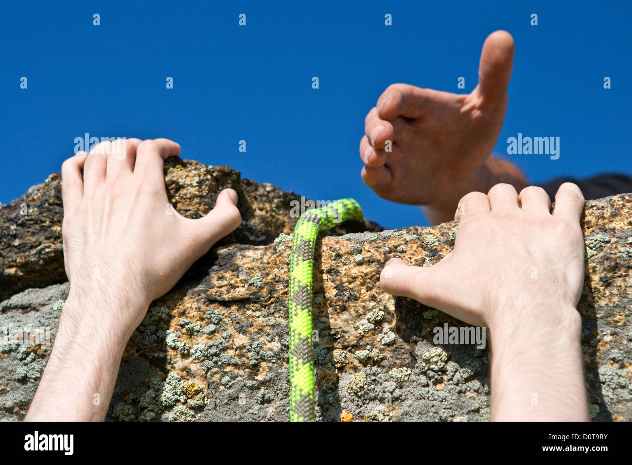 Rock climber reaching for helping-hand partner. Stock Photo