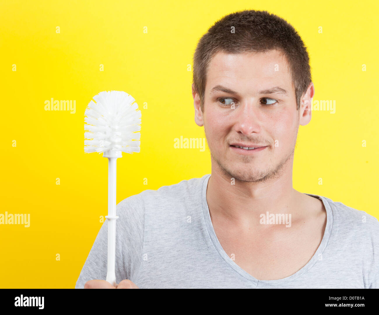 Young man brushing teeth with toilet brush Stock Photo