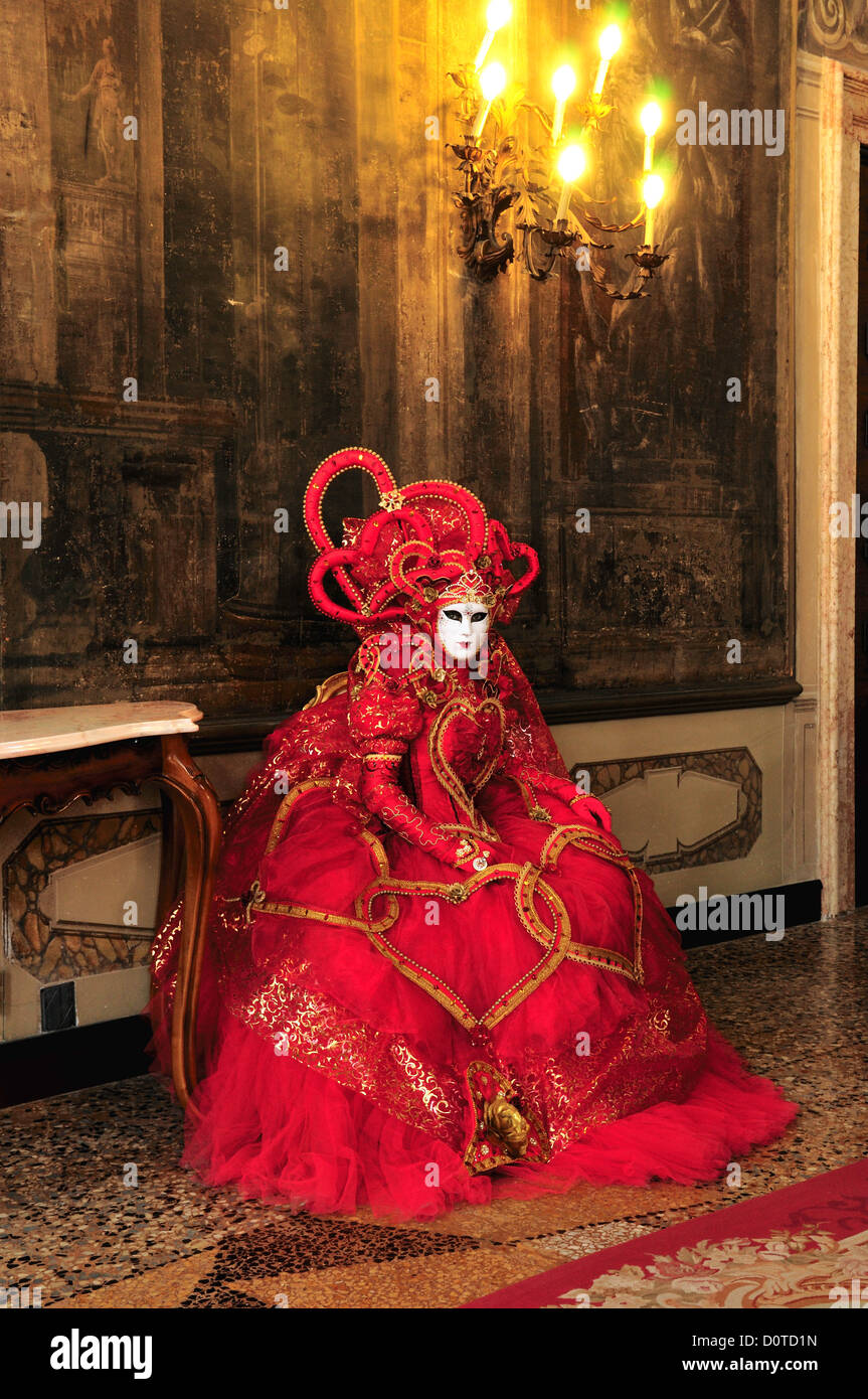 Masked participant seated in the ballroom of a centuries-old palace during Carnival in Venice, Italy Stock Photo