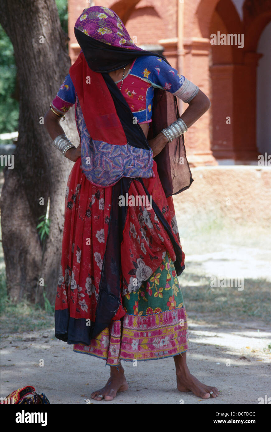 Veiled Rabari woman in traditional dress standing outside. Stock Photo