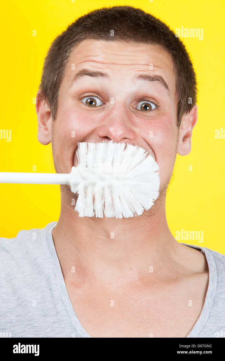 Young man brushing teeth with toilet brush Stock Photo