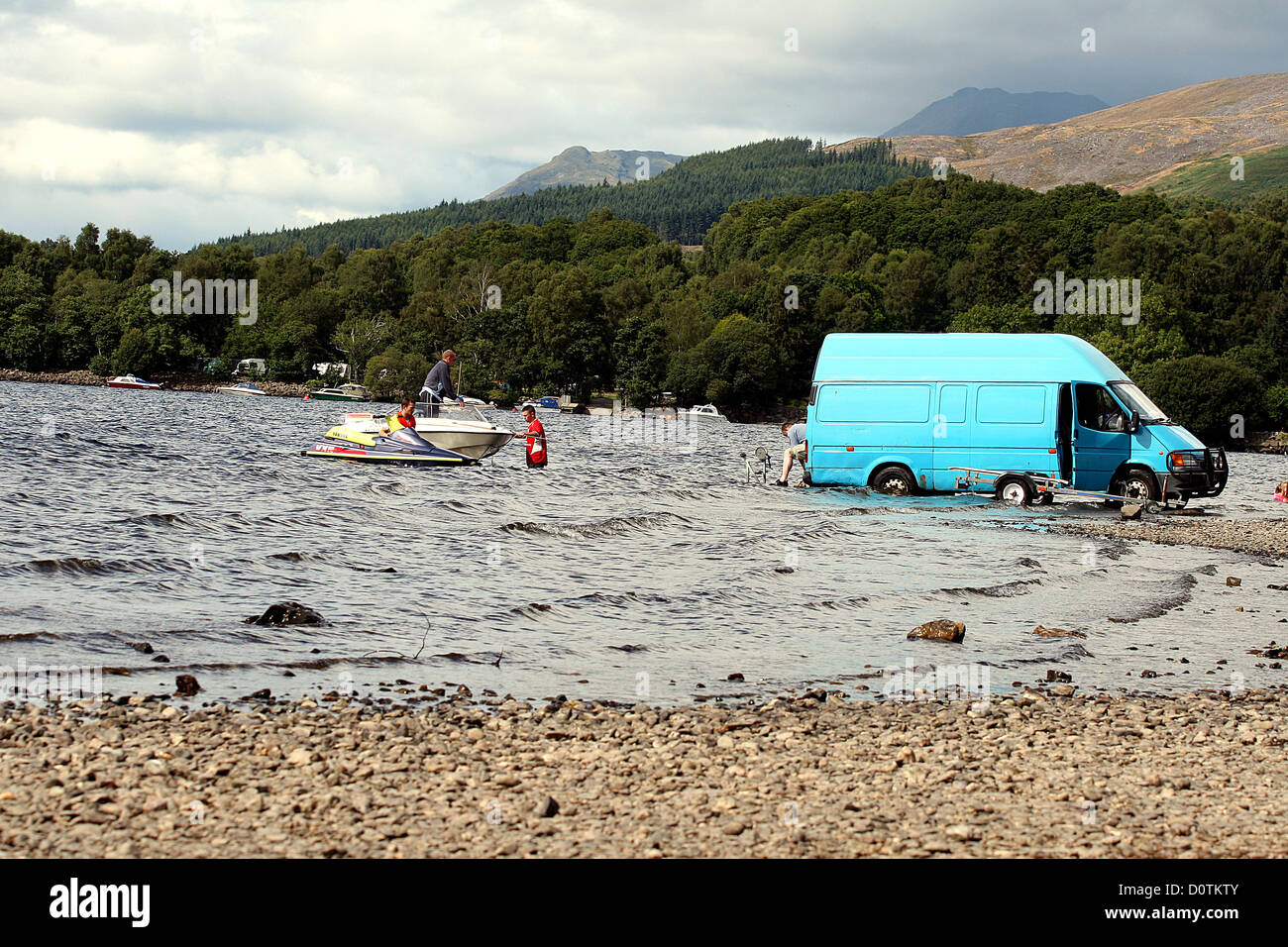 Group of guys bringing a small motor boat ashore from Loch Lomond in