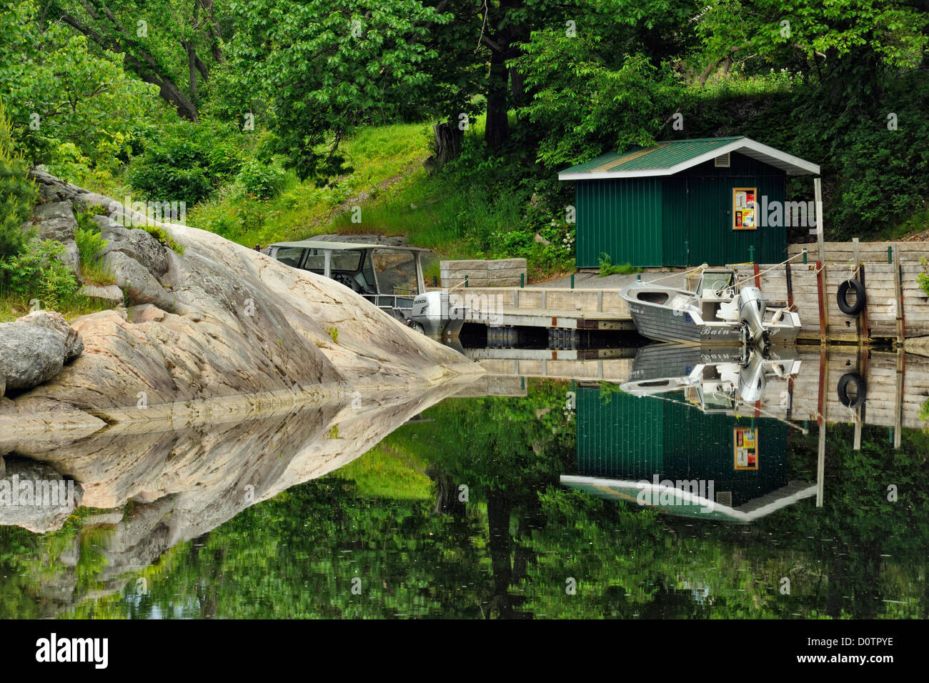 Rock outcrops and village buildings reflected in the Whitefish River