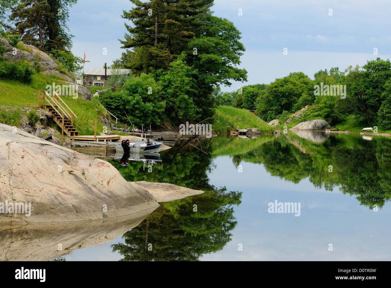 Rock outcrops and village buildings reflected in the Whitefish River