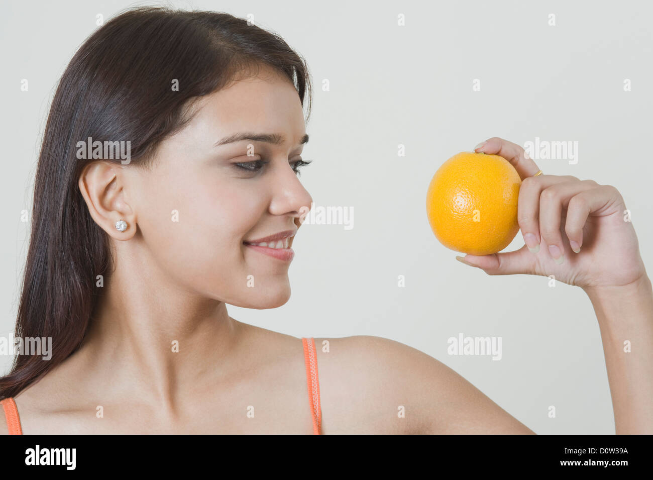 Woman holding an orange and smiling Stock Photo - Alamy