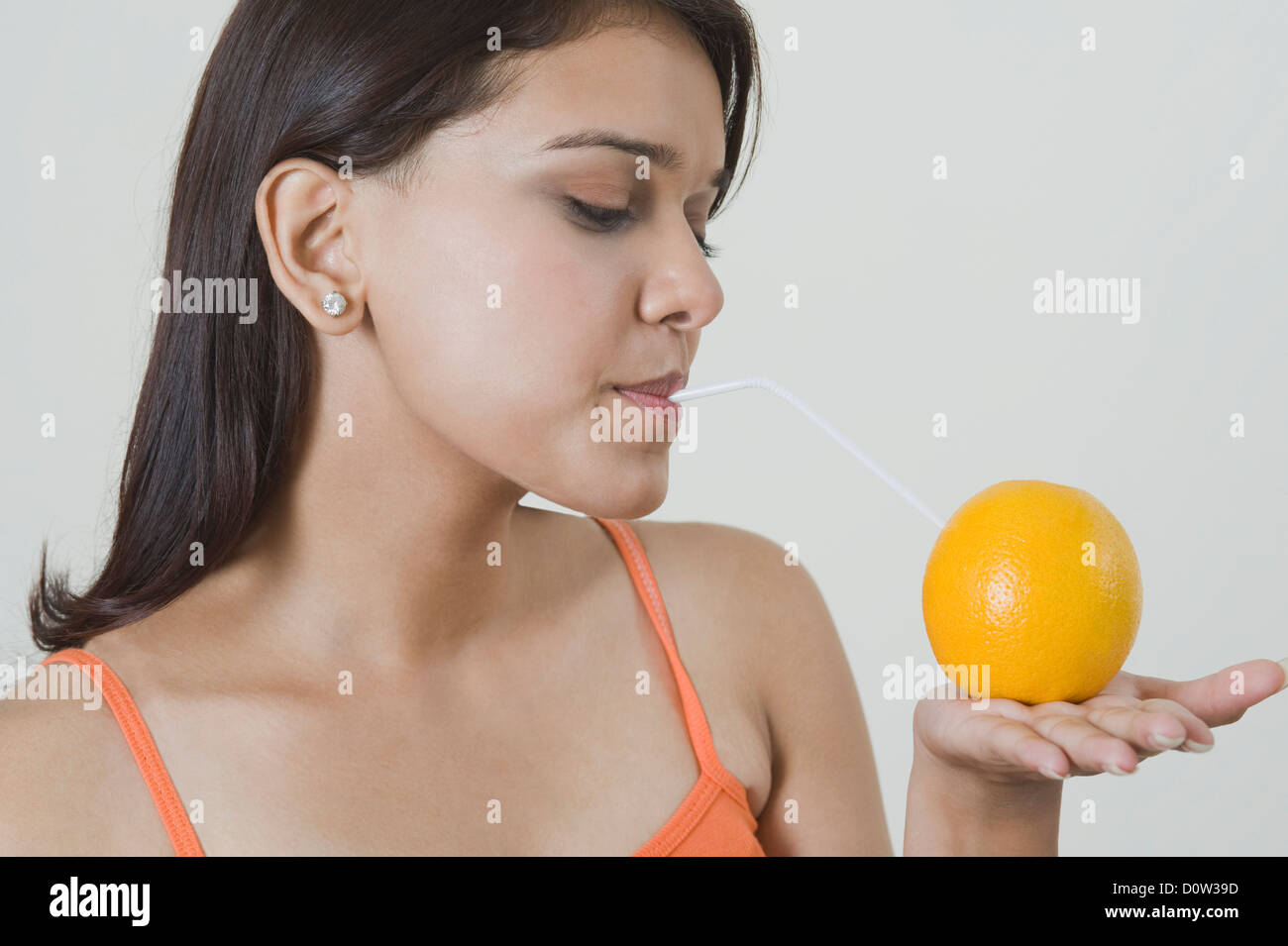 Woman drinking orange juice with a straw Stock Photo Alamy