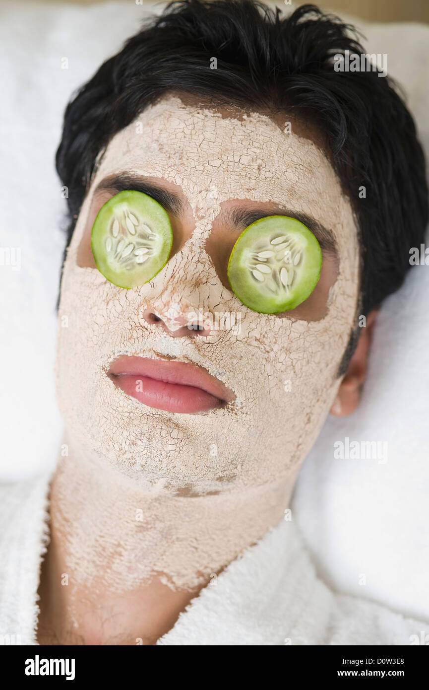 Closeup of a man with facial mask and cucumber slices on eyes Stock