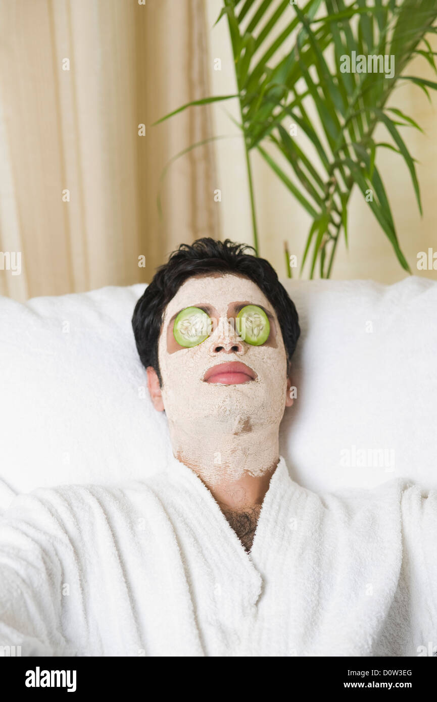 Closeup of a man with facial mask and cucumber slices on eyes Stock