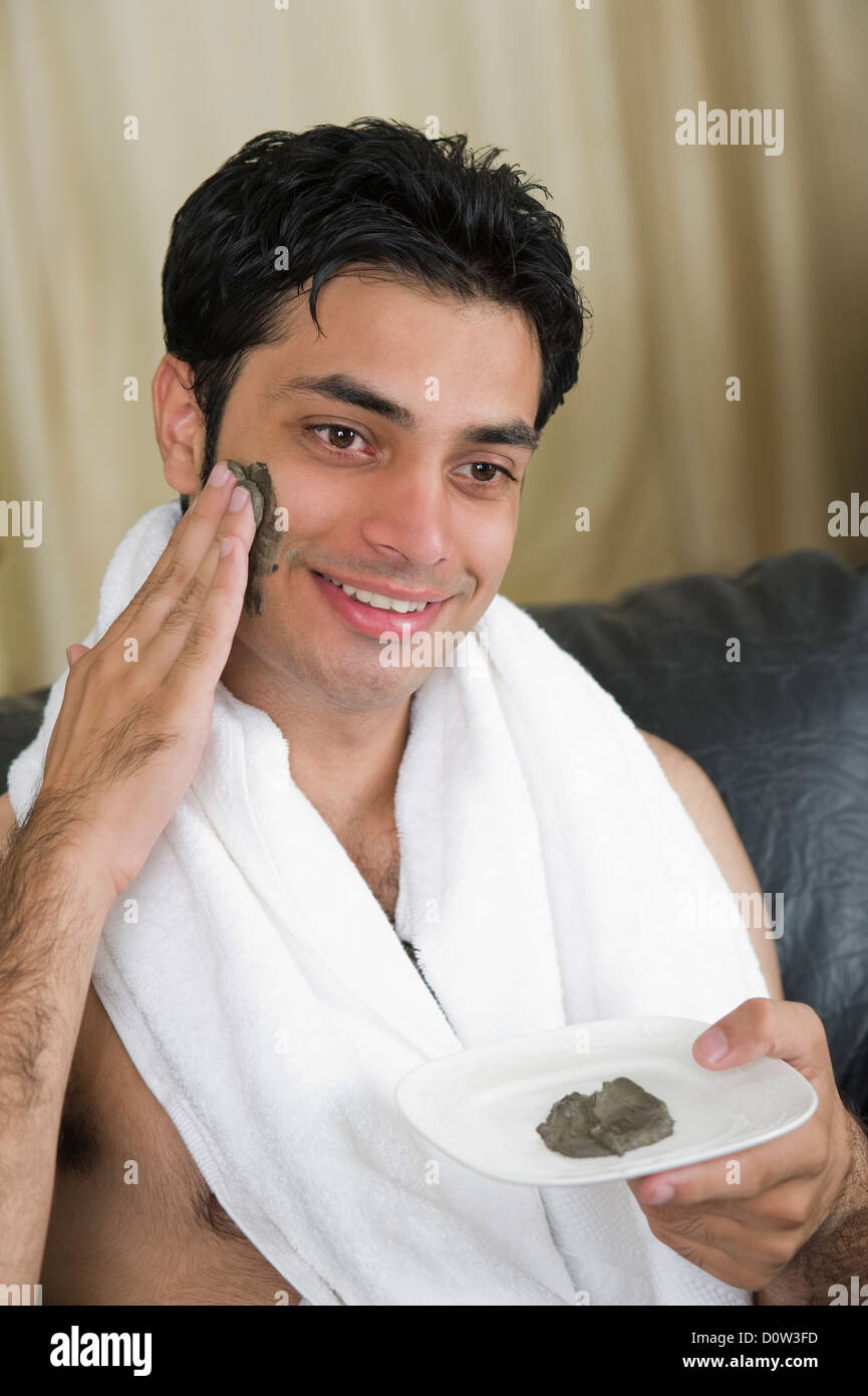 Close-up of a man applying mud pack on his face Stock Photo