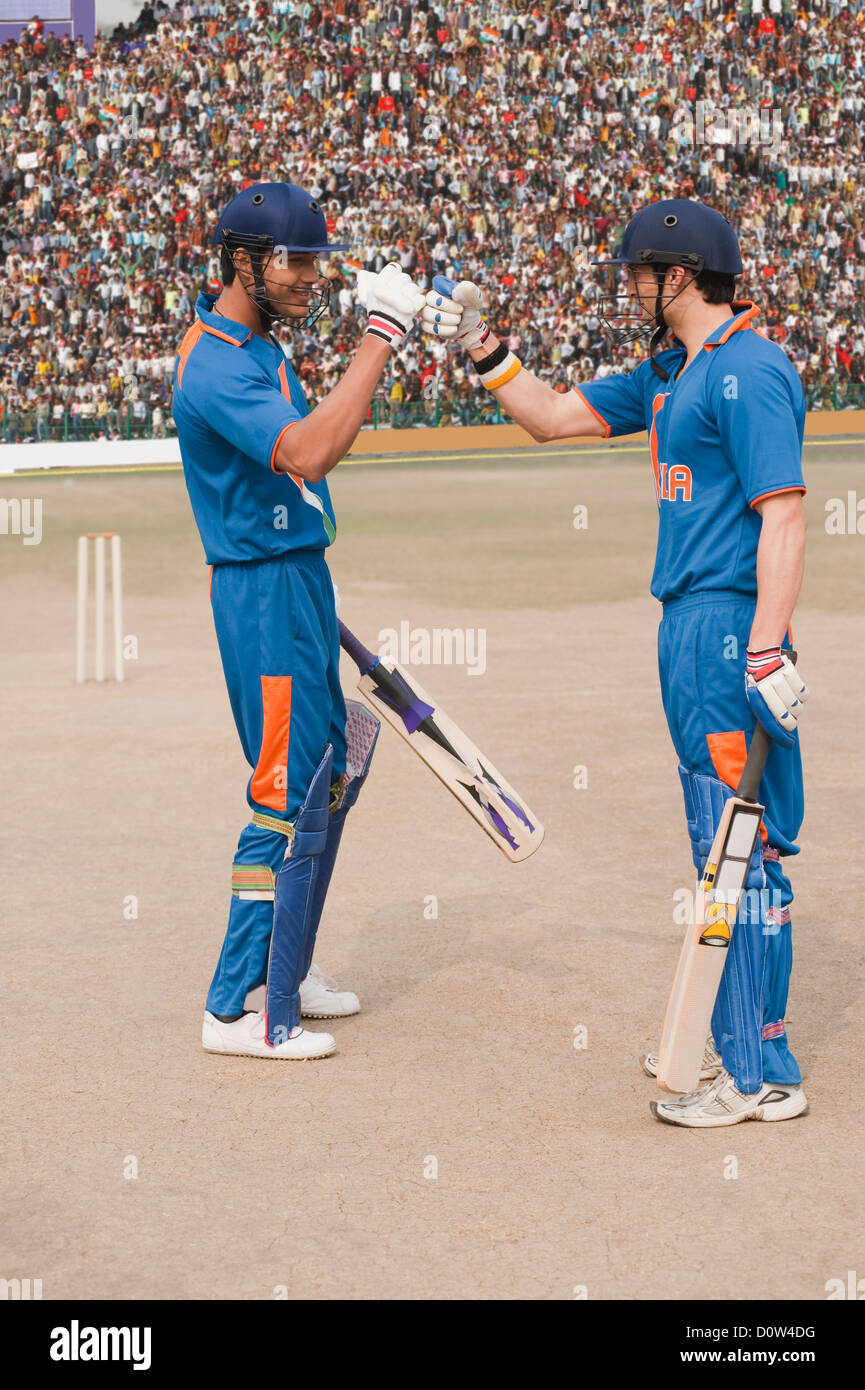 Two cricket batsmen fist bumping each other Stock Photo