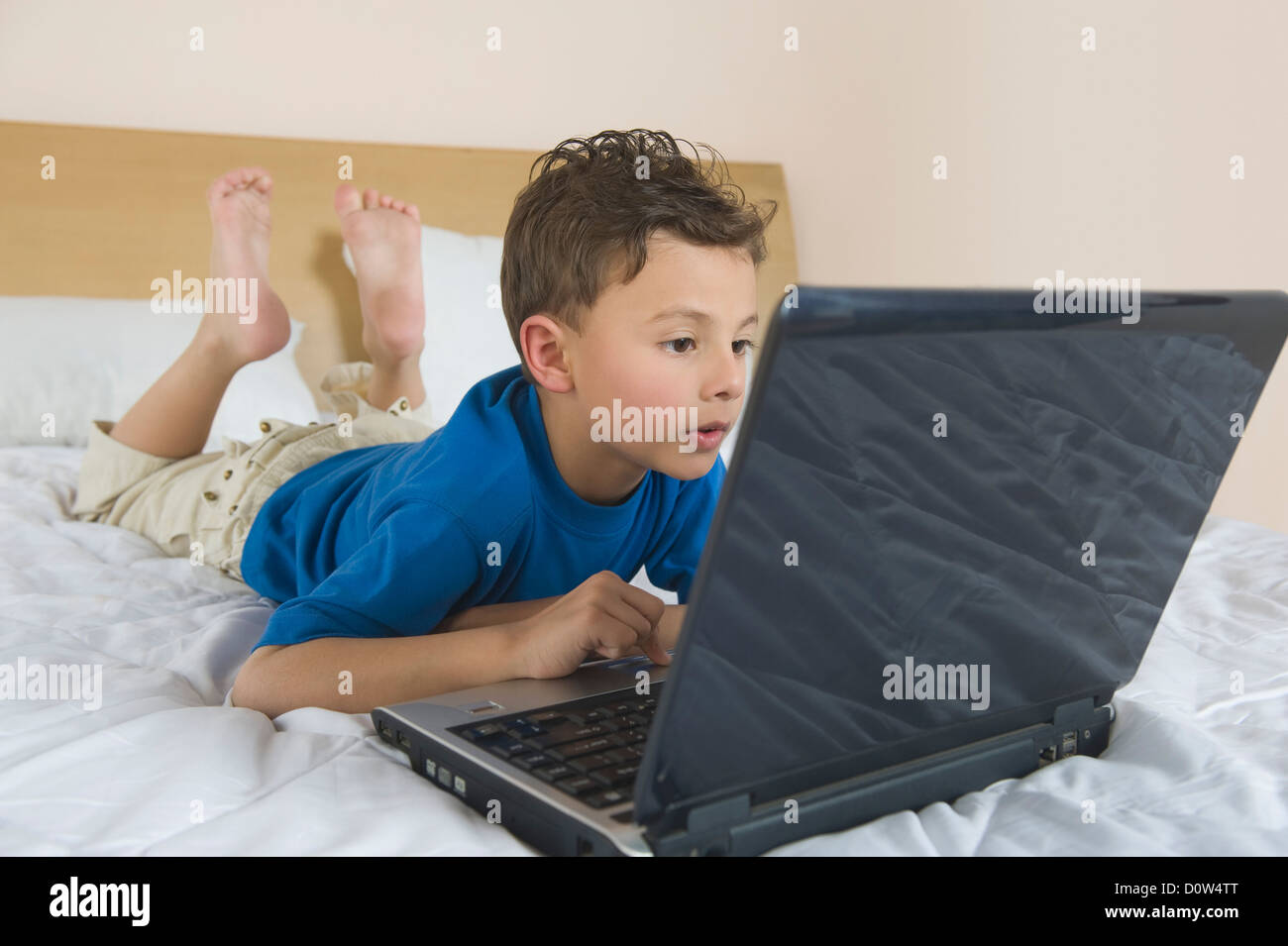 Boy using a laptop on the bed Stock Photo Alamy
