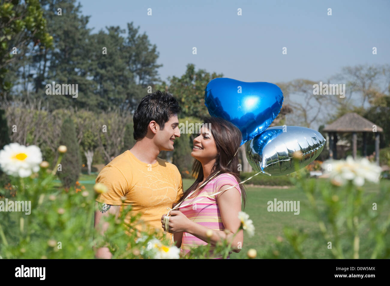 Couple holding balloons and romancing in a garden Stock Photo - Alamy