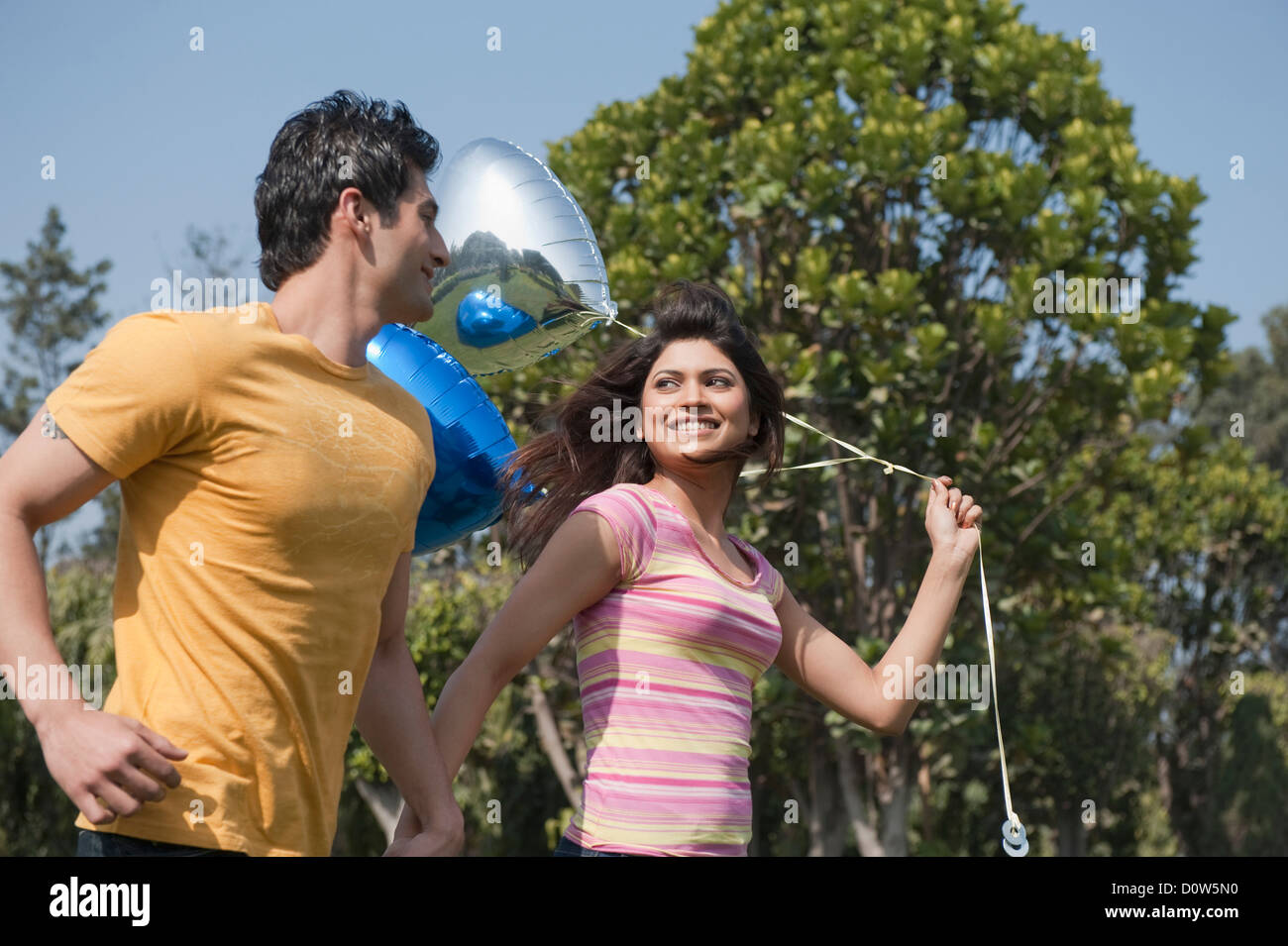Couple holding balloons and romancing in a garden Stock Photo - Alamy