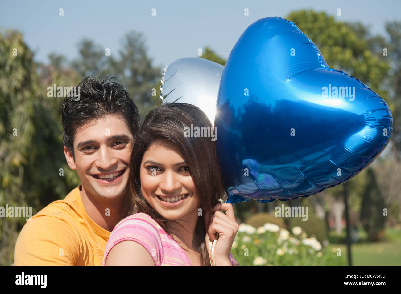 Couple holding balloons and romancing in a garden Stock Photo - Alamy