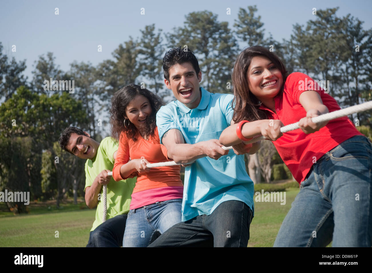 Friends playing tug-of-war in a garden Stock Photo