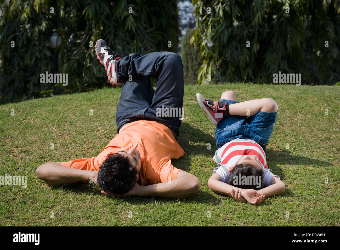 Man lying with his son in a lawn, Gurgaon, Haryana, India Stock Photo