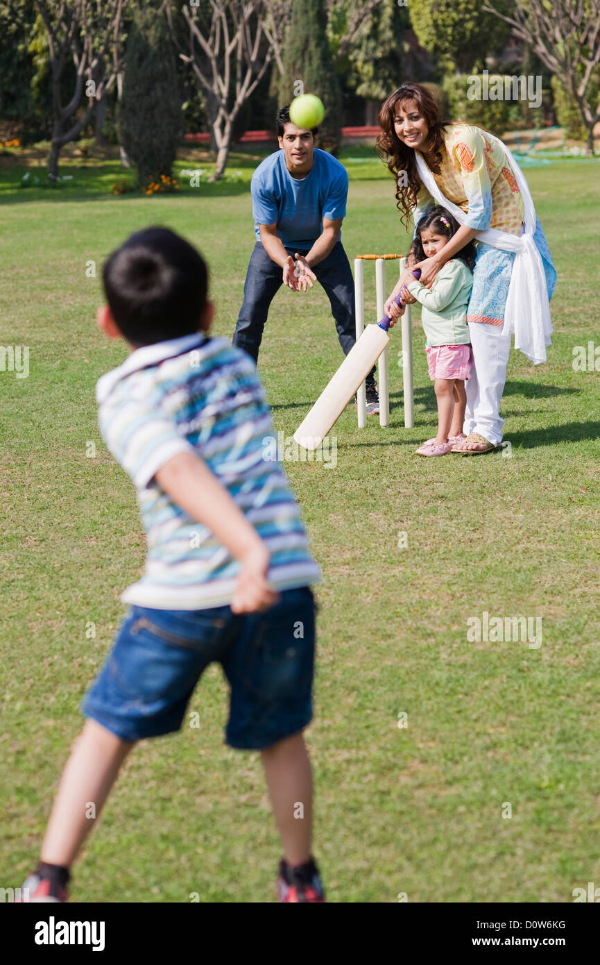 Family playing cricket in a lawn, Gurgaon, Haryana, India Stock Photo