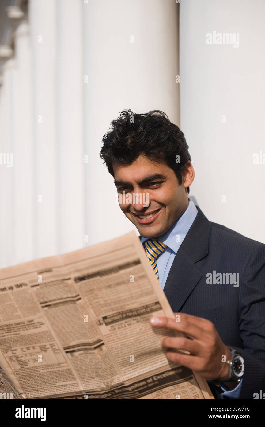 Businessman reading a newspaper, Gurgaon, Haryana, India Stock Photo