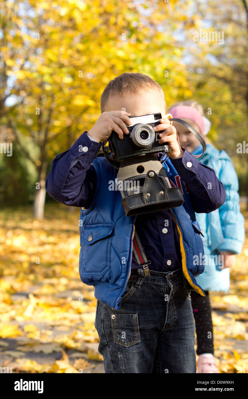 Little boy playing at being an aspiring young photographer holding a vintage camera to his eye Stock Photo