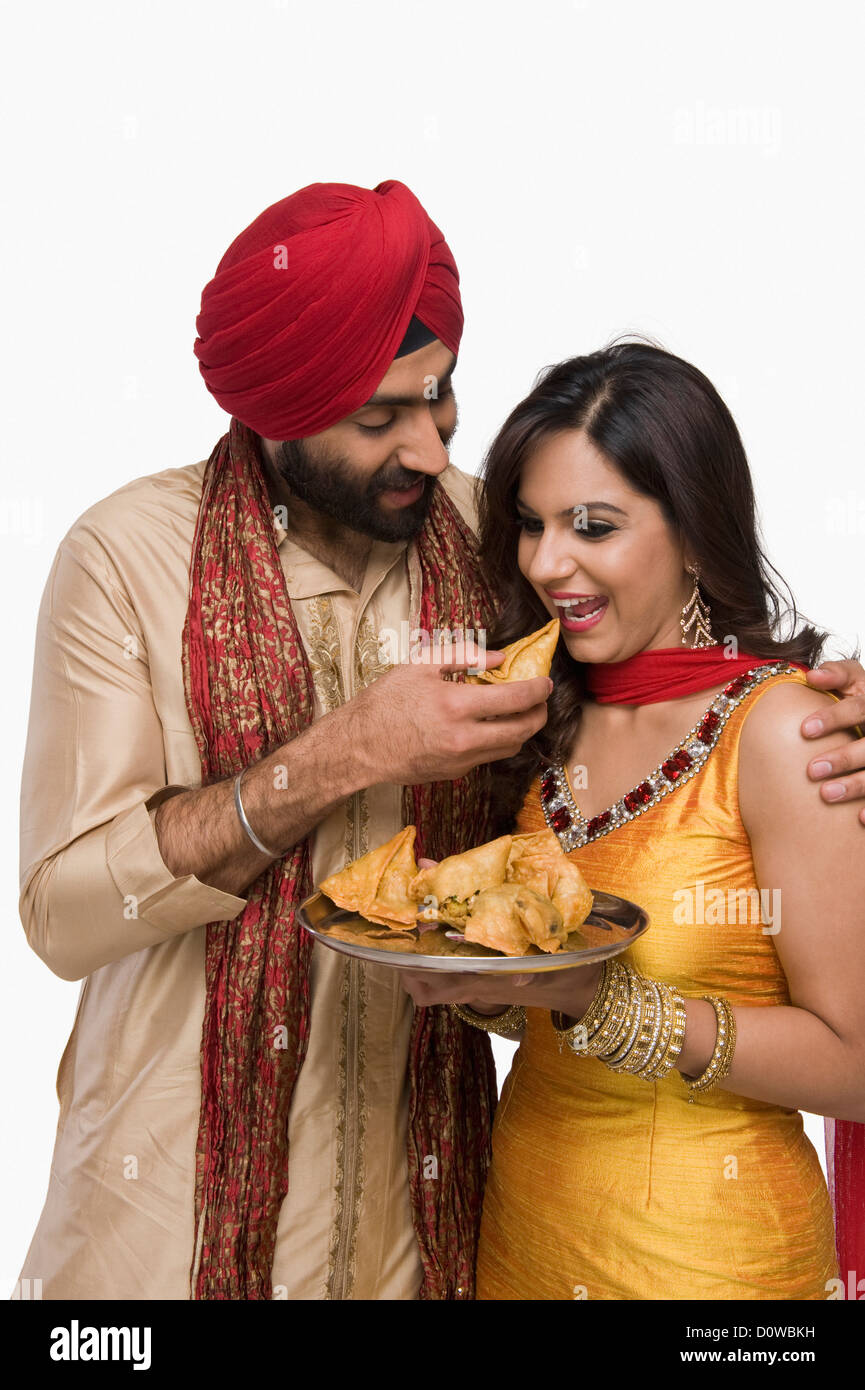 Sikh man feeding samosa to his wife Stock Photo