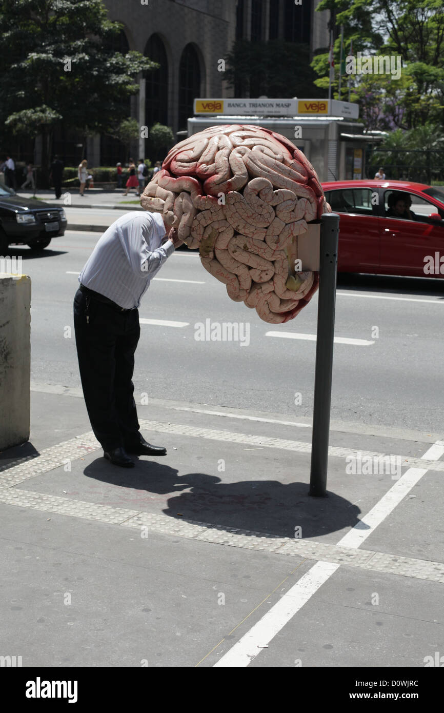 A person looks at one of the artistic phone boxes shaped like a brain, on Avenida (Avenue) Paulista, Sao Paulo, Brazil 2012 Stock Photo