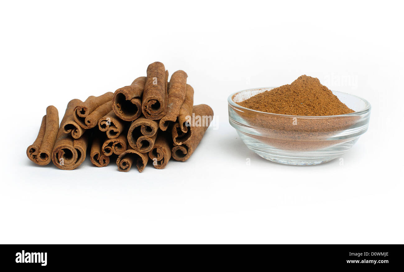Powdered cinnamon in bowl and cinnamon sticks on white background Stock Photo