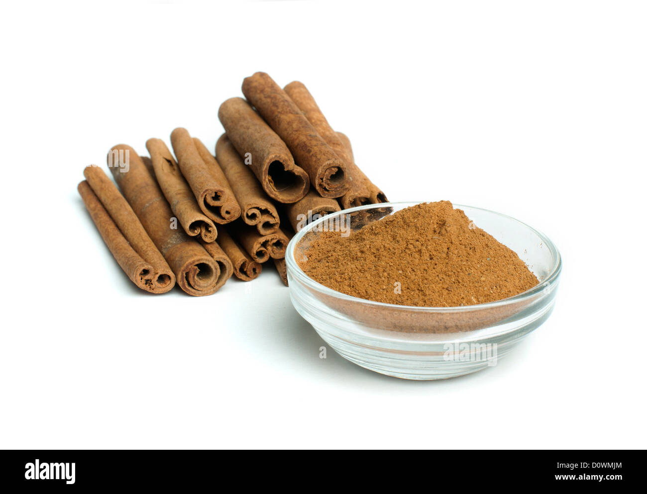 Powdered cinnamon in bowl and cinnamon sticks on white background Stock Photo