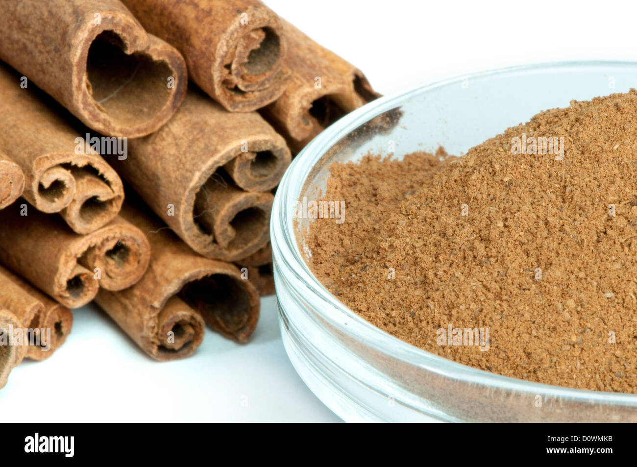 Powdered cinnamon in bowl and cinnamon sticks on white background Stock Photo