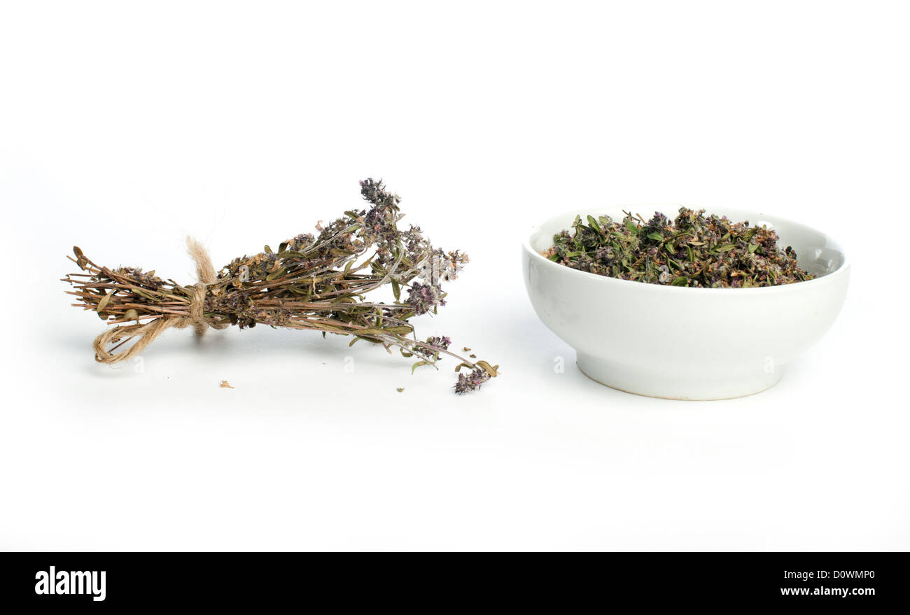Dried thyme in a bowl and thyme twigs on white background Stock Photo