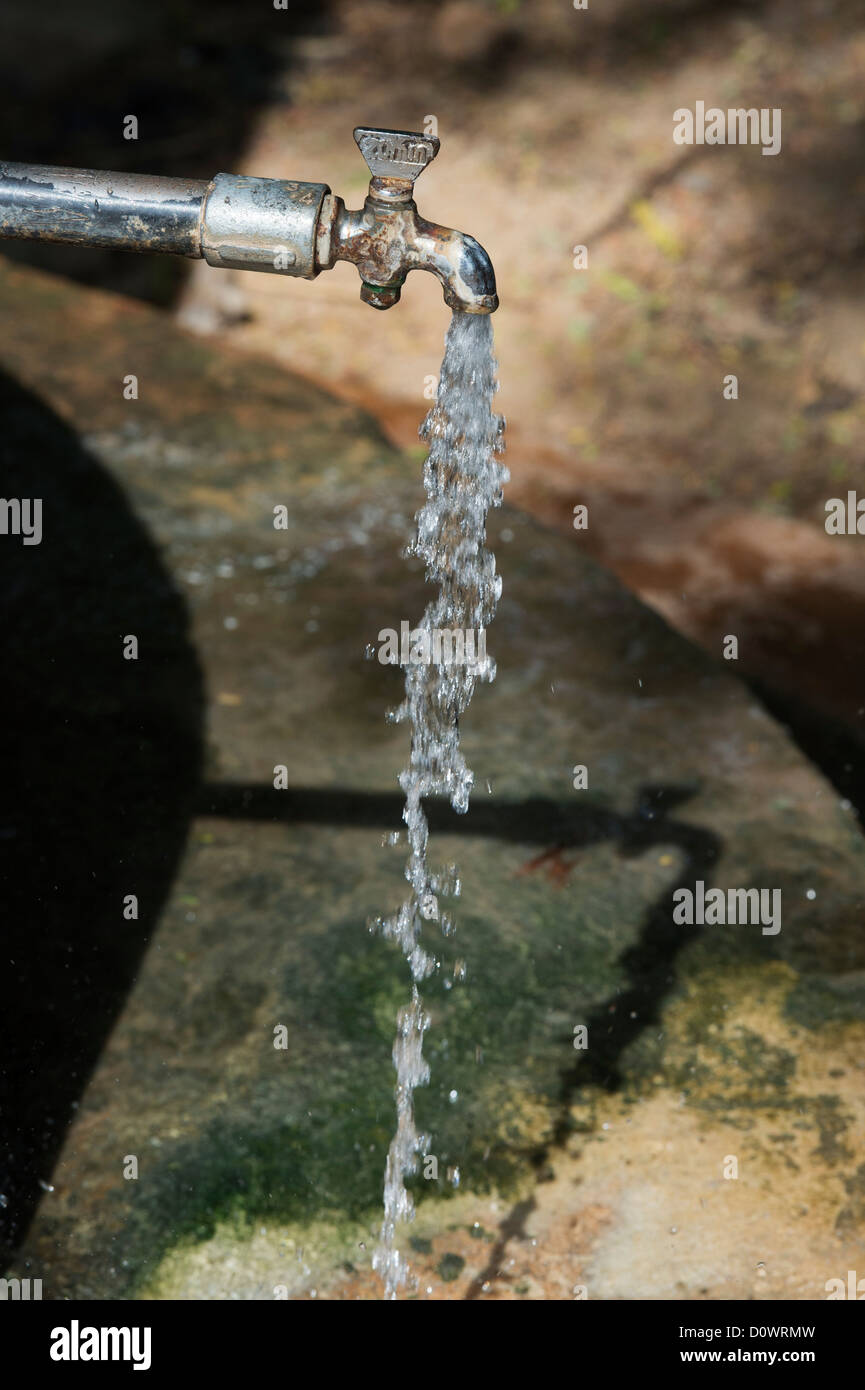 Water comming out of a communal water tap with shadow in rural indian