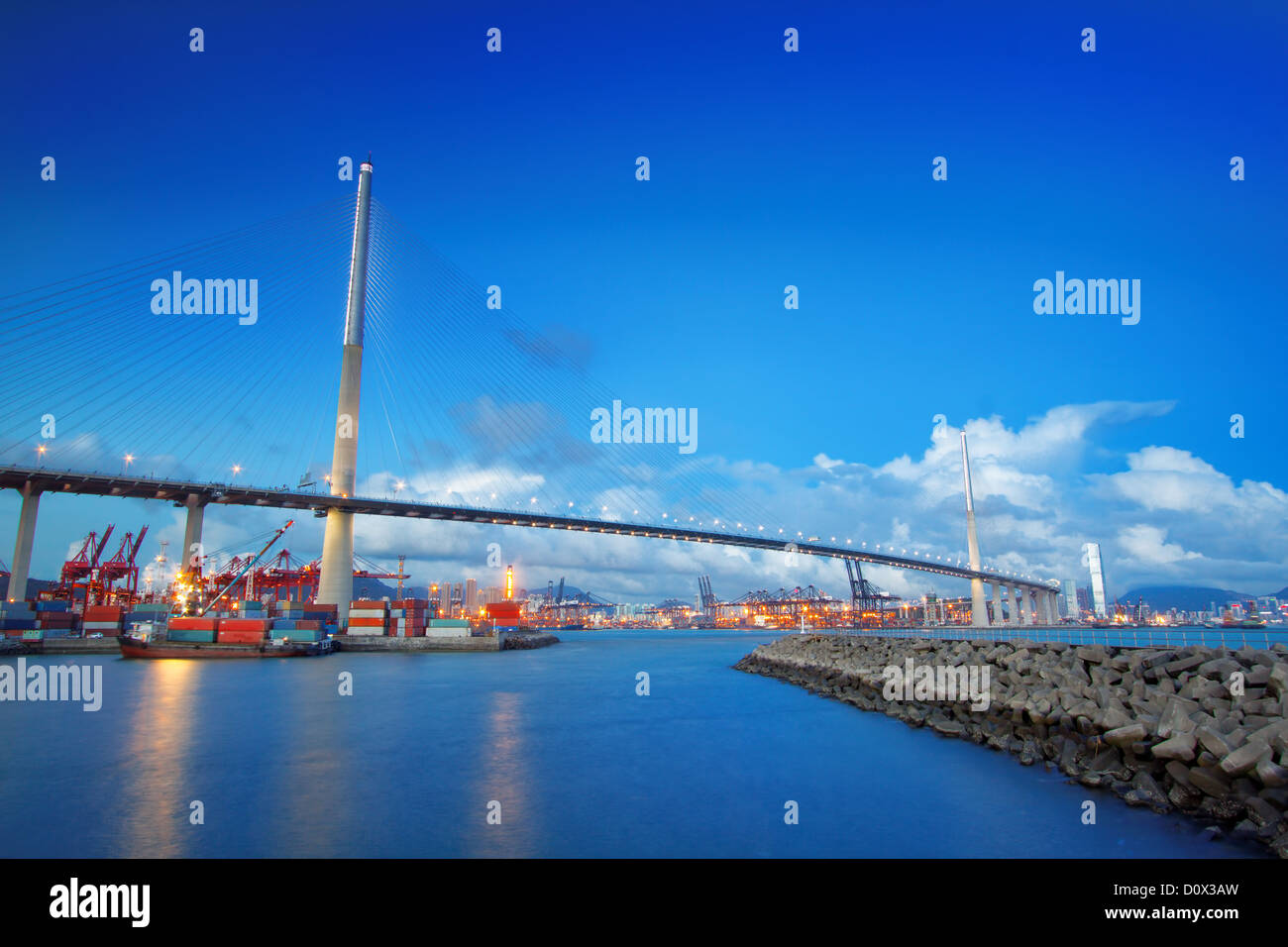Port warehouse with containers and industrial cargoes , view under bridge on water break at sunset Stock Photo