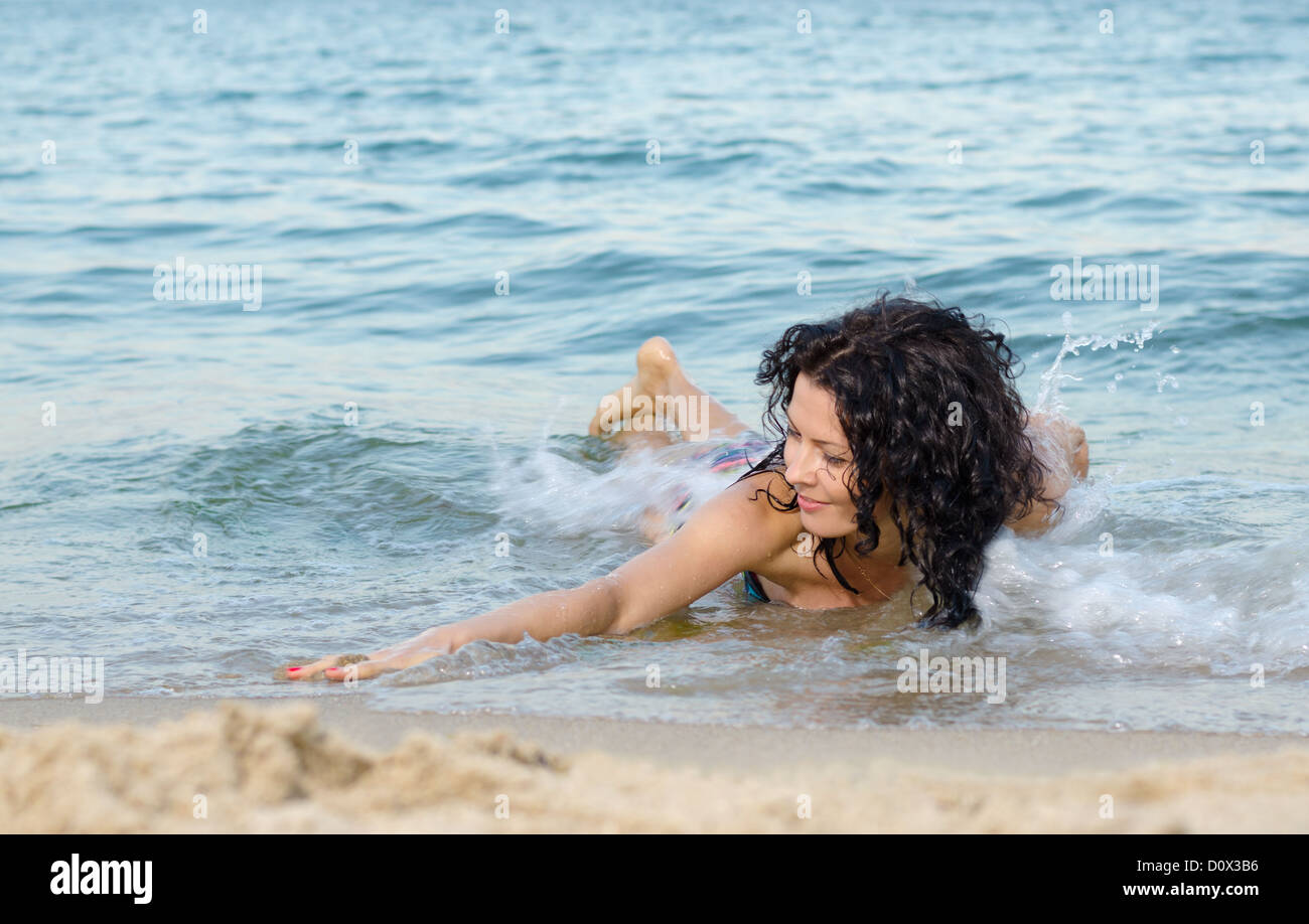 Beautiful brunette woman frolicking in the shallow surf on a tropical beach Stock Photo