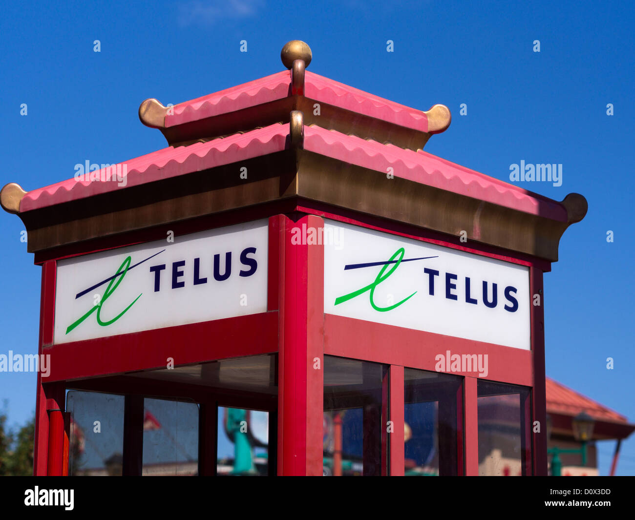 Phone booth with a Chinatown Makeover. Curled double roof dresses up a red telus phone booth in Edmonton's Chinatown. Stock Photo