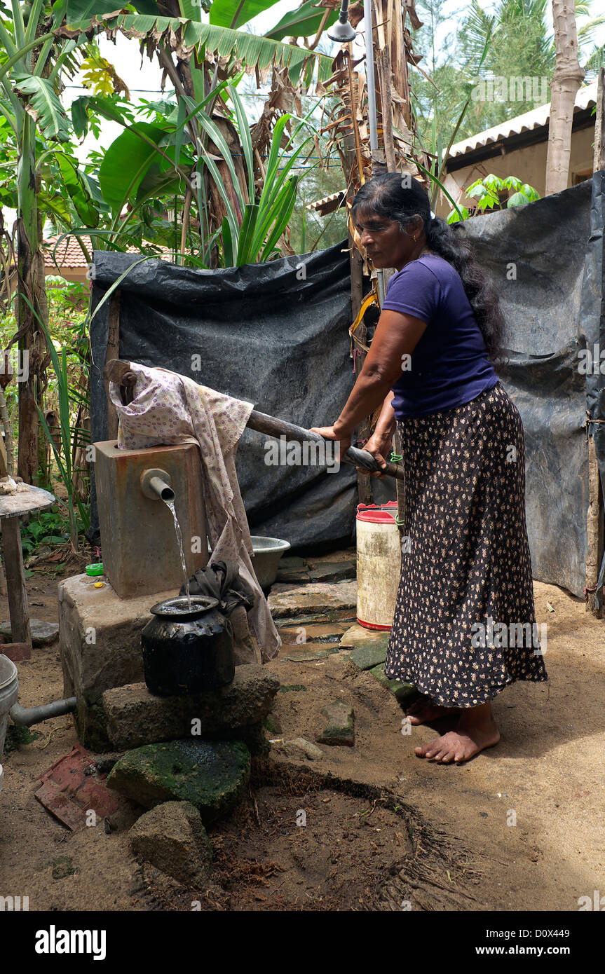 Woman in the village of Waikkal, Sri Lanka, pulling water from a well using and old hand pump