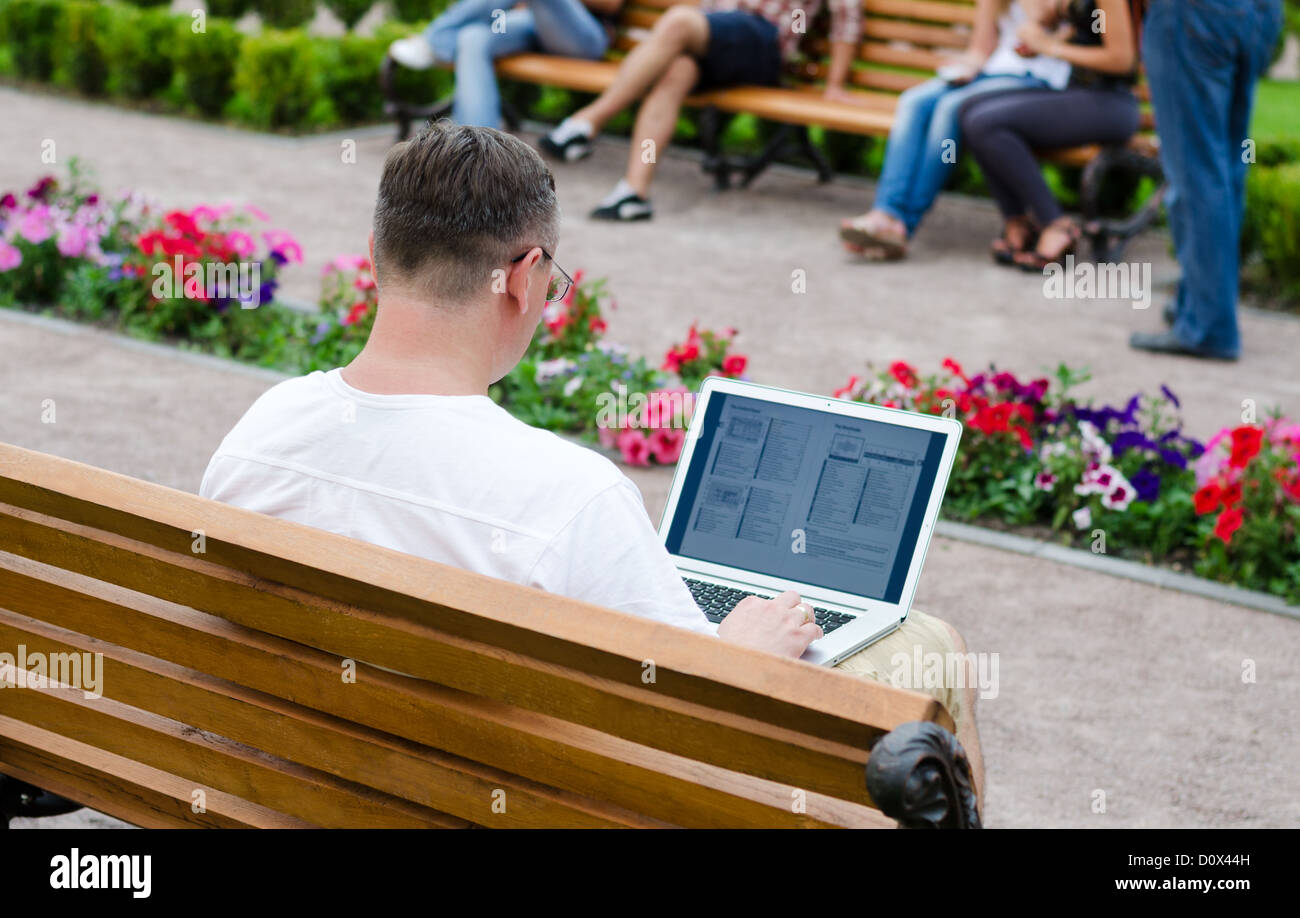 Over the shoulder view onto the screen of a man using a laptop computer in a public park Stock Photo