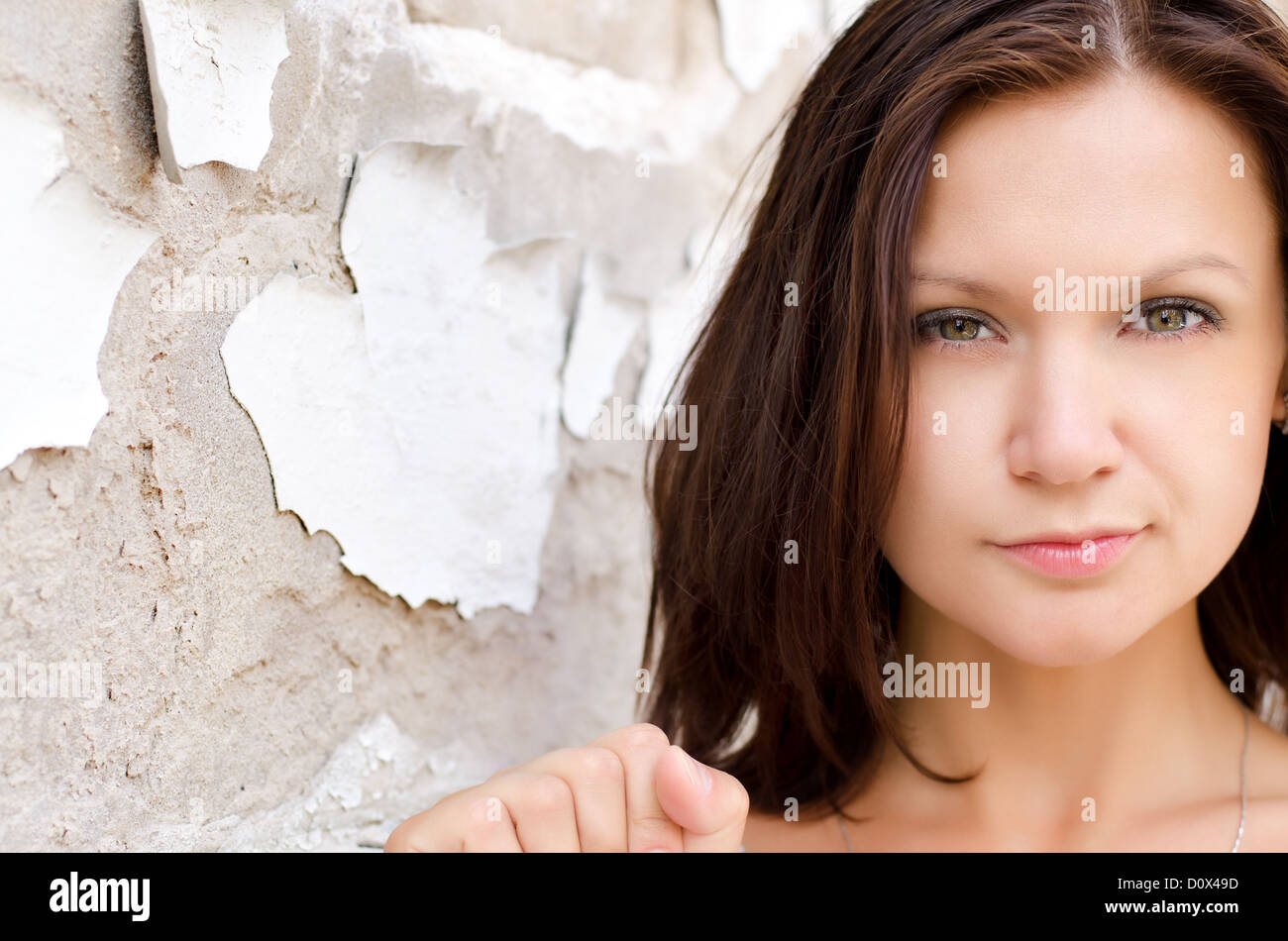Headshot of a beautiful woman posing againsta grunge wall with peeling paint and exposed concrete Stock Photo