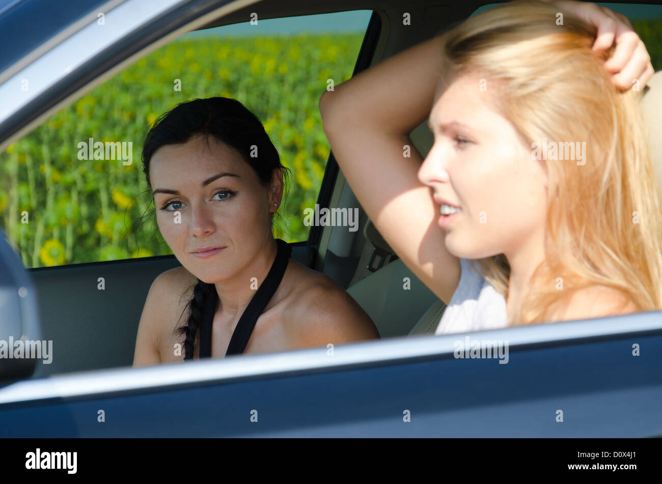 View through past the female driver to an attractive woman passenger in a motor car with focus to the passenger Stock Photo