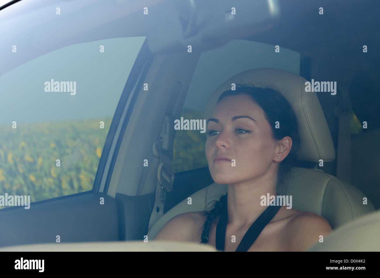 View of a beautiful woman sitting in the passenger seat of a car looking through the windscreen Stock Photo