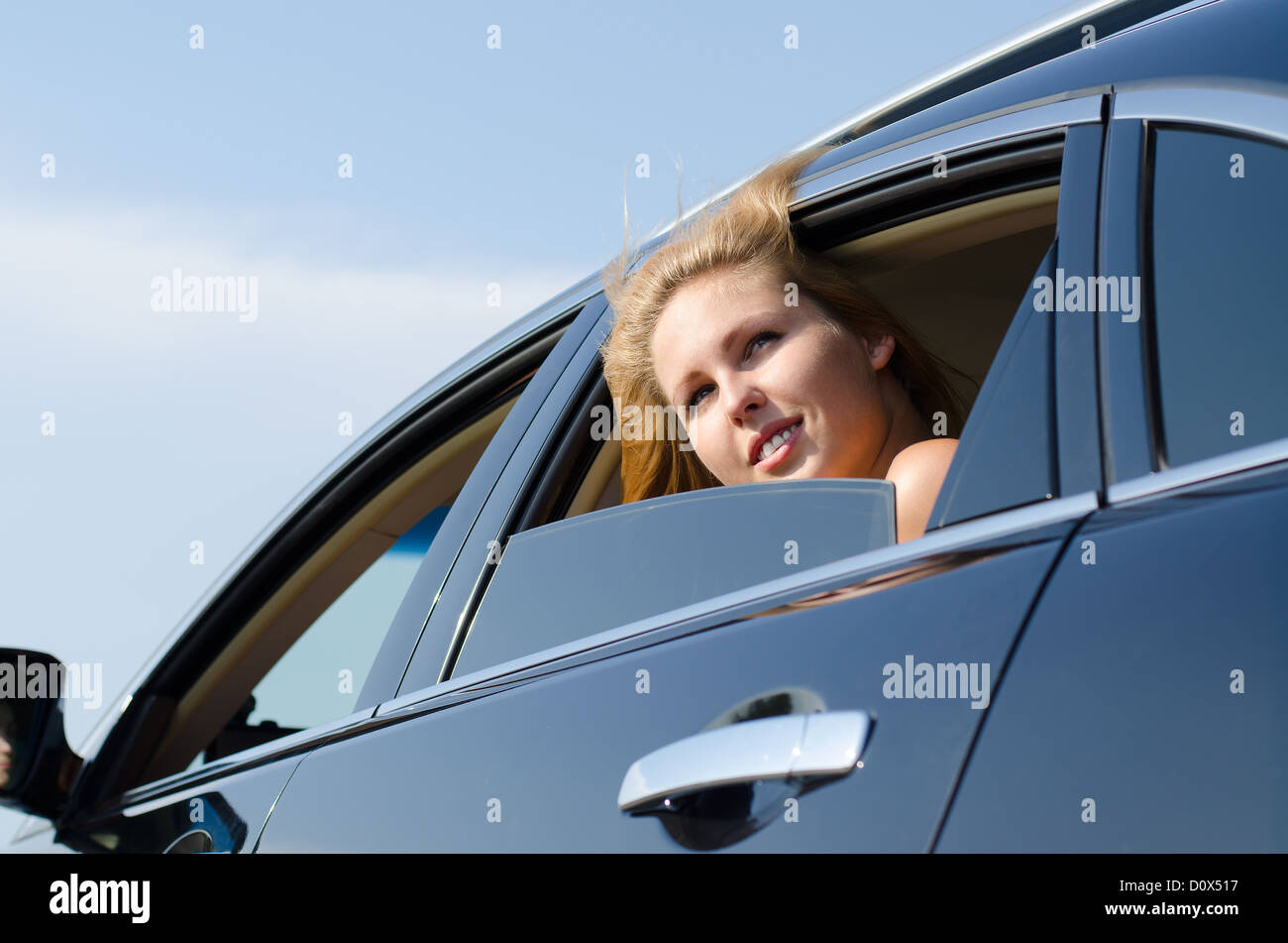 Low angle view of a young woman car passenger peering out of the open window of the vehicle Stock Photo