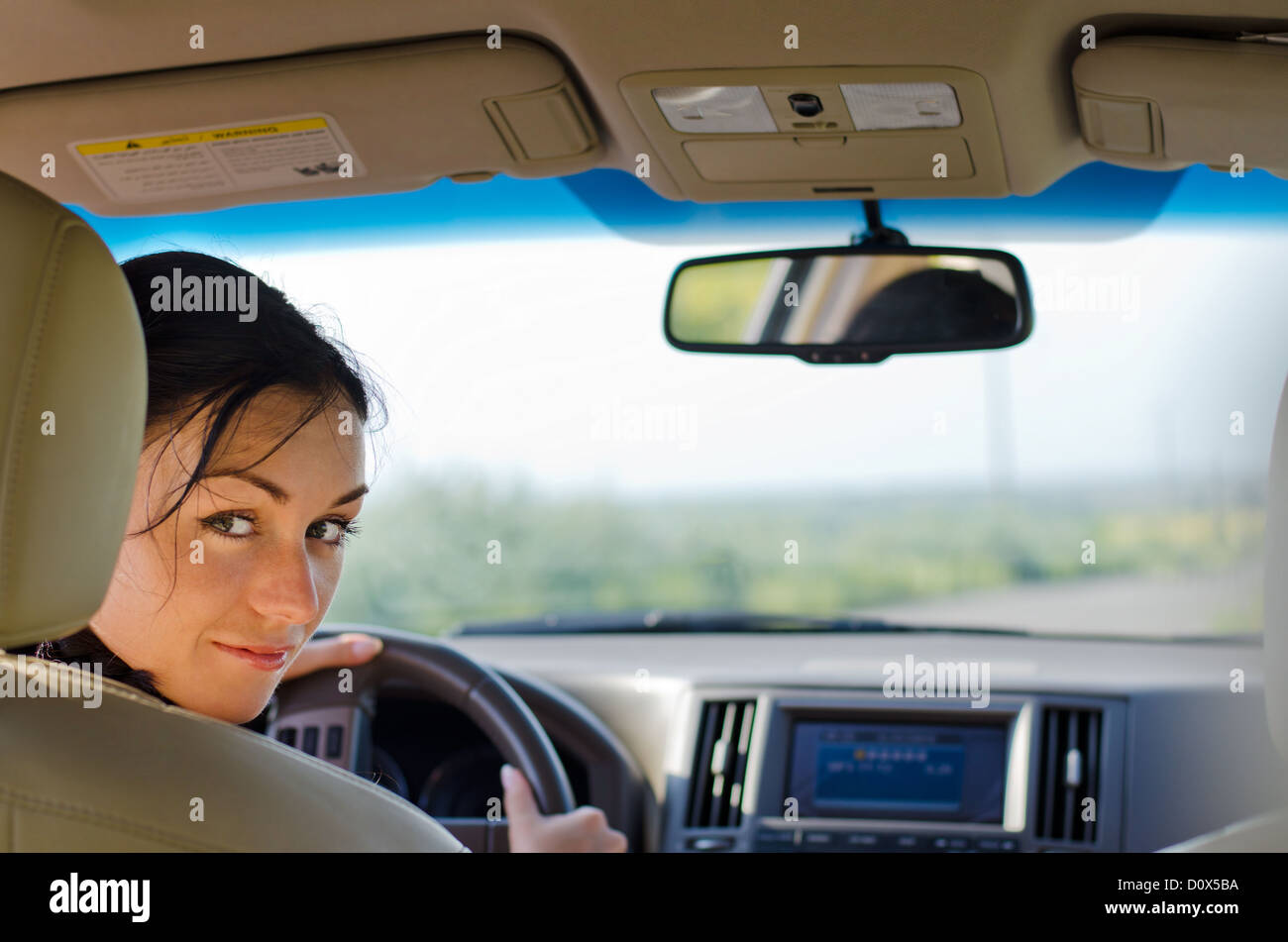 Woman driver looking over the back of the drivers seat into the rear of the car breaking her concentration on the road Stock Photo