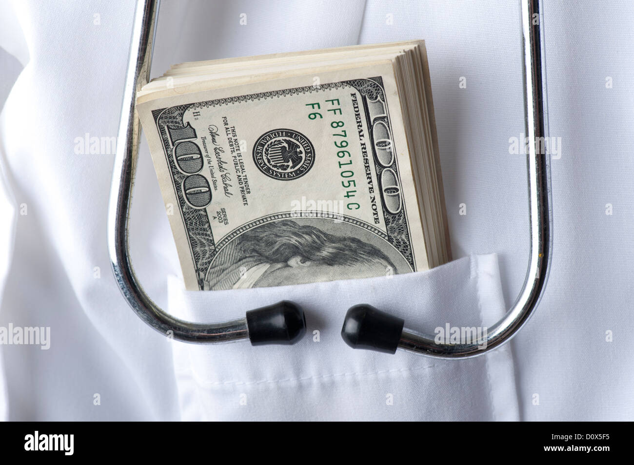 conceptual image medical stethoscope and $100 bills in  doctor's pocket Stock Photo