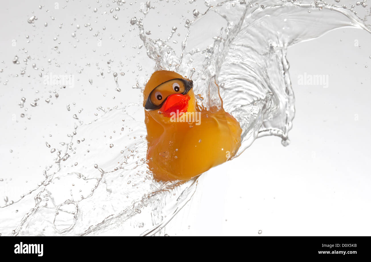 yellow rubber duck wearing goggles surfing in water splash Stock Photo