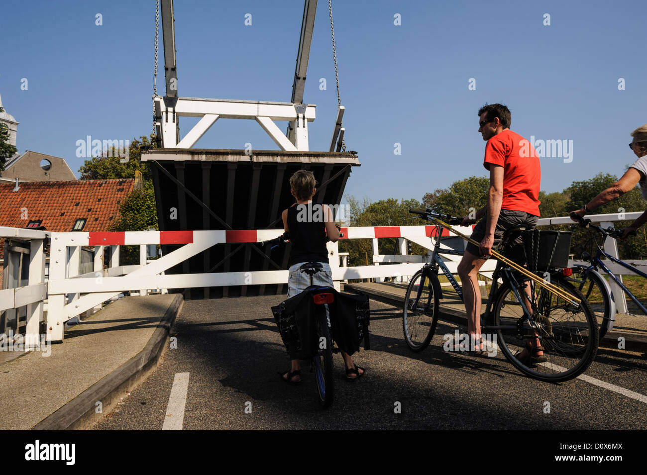 Cyclists waiting by bascule bridge, the Netherlands Stock Photo