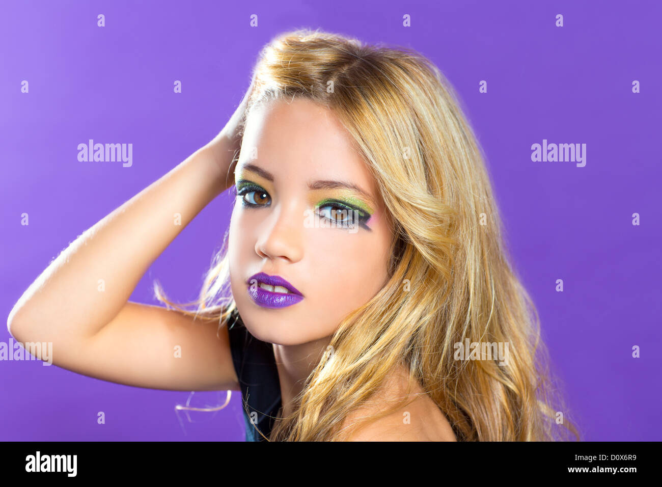 Blond children fashiondoll girl fashion makeup on purple background Stock Photo