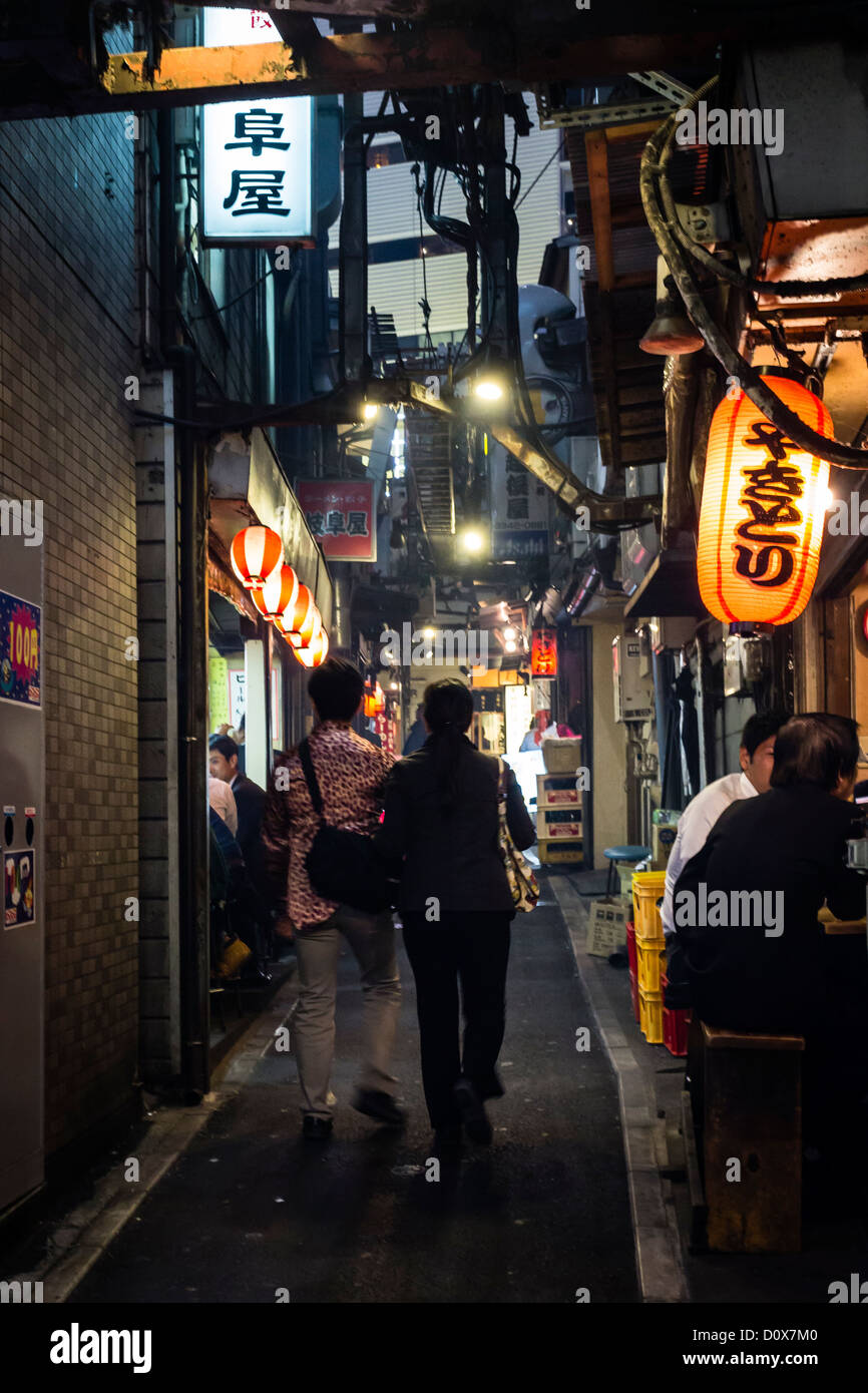 A couple walks through an alley filled with restaurants near shinjuku station Stock Photo