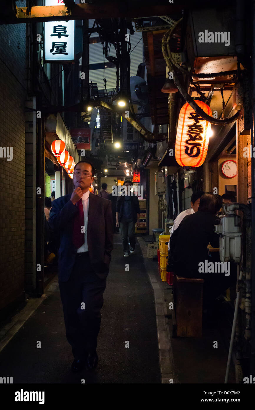 Near Shinjuku station, on an alley filled with yakitori restaurants, a man walks by looking for a place to dine after work. Stock Photo