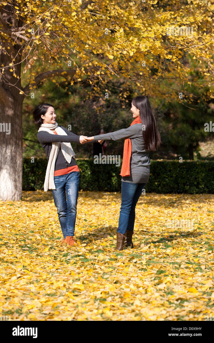 Two happy young women holding hands on the lawn in autumn Stock Photo ...